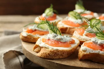 Gordijnen Tasty canapes with salmon, cucumber, cream cheese and dill on wooden stand, closeup © New Africa