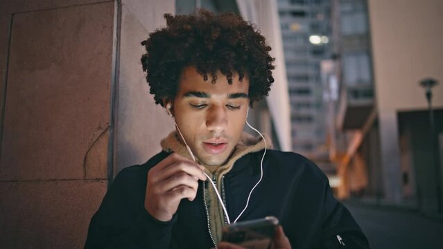 Relaxed man talking smartphone using headphones in urban dusk closeup. 