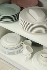 Outdoor kussens Clean plates, butter dish and cups on shelves in cabinet indoors © New Africa