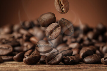 Roasted coffee beans falling on wooden table, closeup