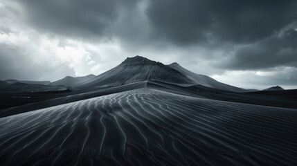Stark black sand dunes rippling toward a mountain shrouded in misty clouds