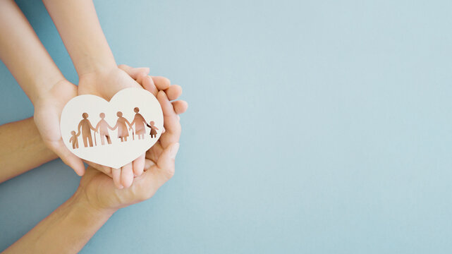 Hands holding multi generational family in heart shape paper, family wellness, health insurance concept