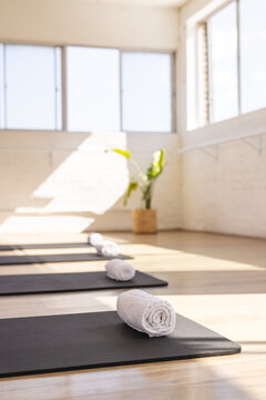 Sunlight filling bright yoga studio, mats and towels neatly arranged, copy space