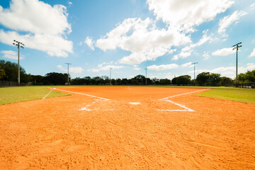 Empty Softball Field under blue sky with scattered clouds. - obrazy, fototapety, plakaty