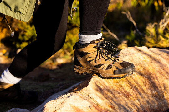 Biracial female hiker wearing hiking boots walking on rocks