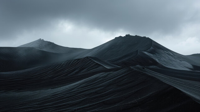 Monochrome majesty of black sand dunes rise to fill the expanse of cloudy clouds
