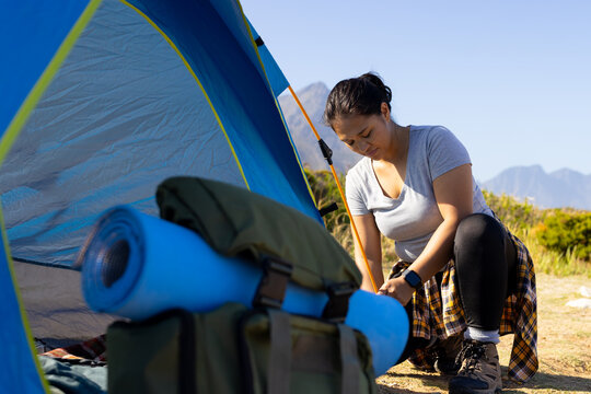 Biracial female hiker wearing casual clothes setting up a tent
