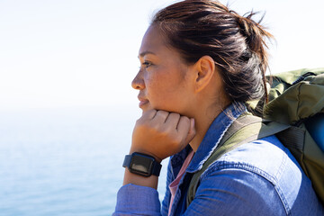 Biracial female hiker looking thoughtful, wearing a backpack, with copy space, adventure in nature