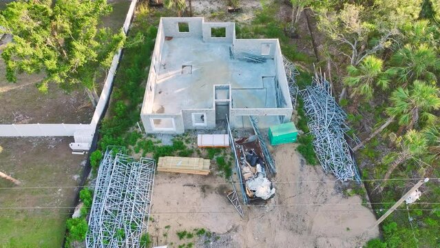 New house under construction. Aerial view of incomplete frame of private home with brick concrete walls ready for installation of wooden roofing beams. Industrial building site