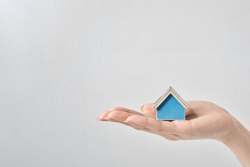 女性の手のひらに乗せられた住宅模型