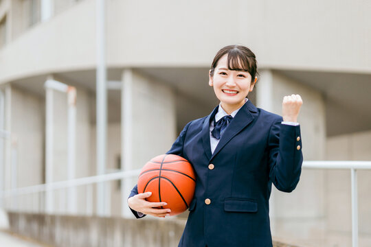 校舎の前でバスケットボールを持つ女子中学生・女子高生（部活・スポーツ・運動部・バスケ部）
