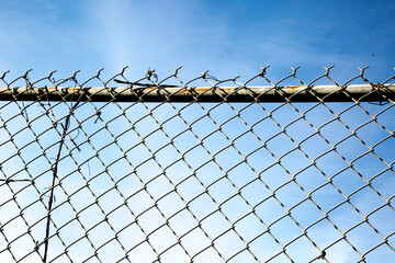 The jagged top of a chain link fence