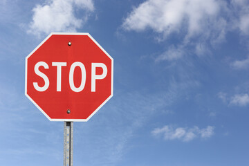 A stop sign isolated on a blue cloudy sky