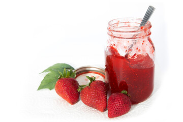 A mason jar of homemade strawberry jam with strawberries isolated on white