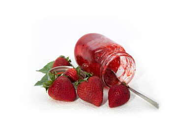 a mason jar of homemade strawberry jam on its side with strawberries isolated on white