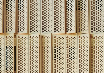 Gold perforated cladding shutters on the outside of a building