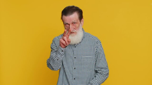 I am watching you. Confident attentive senior old man grandpa pointing at eyes and camera, show I am watching you gesture, spying on someone. Elderly bearded grandfather isolated on yellow background