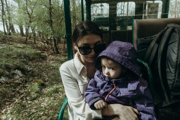 Portrait of a young woman with a little girl sitting in an open train carriage.