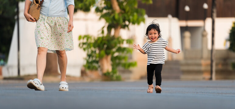 happy toddler girl running with her mother in park