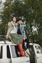 Stylish couple sitting on top of the retro bus and posing for a photo