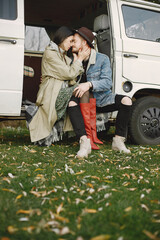 Stylish couple sitting in a retro bus and posing for a photo