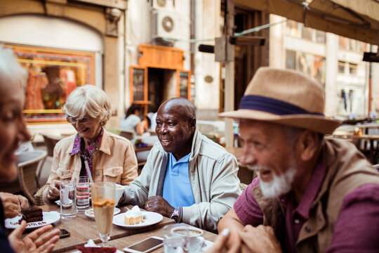 Senior friends laughing at outdoor cafe - Powered by Adobe