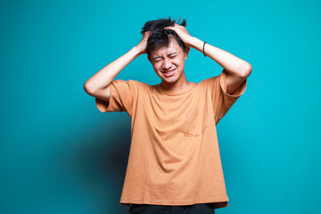 Stressed Young Man Hands Holding Head Isolated on Blue Background - obrazy, fototapety, plakaty