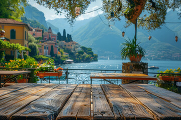 An empty wooden tabletop has a blurred background of a village by the lake, featuring quaint buildings and cafe tables.