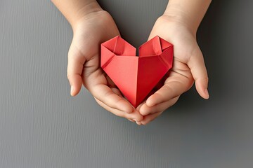 hilds hands holding red paper heart on