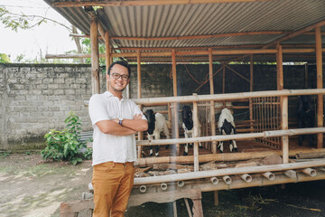 Excited young Asian man standing in front of traditional cage made from wood and bamboo in...