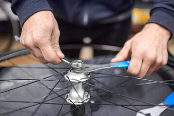 Unrecognizable person assembling a bike wheel axle after disassembling it for cleaning and greasing...