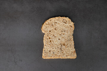 Top view of a piece of grain loaf bread on balck background