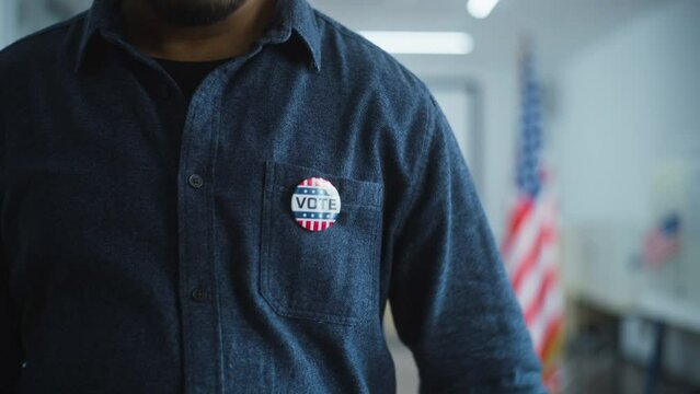 Anonymous African American male voter or businessman puts on badge with USA flag logo and inscription I Voted. US citizen at polling station during elections. National Election Day in United States.