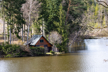 A cottage on the shore of the lake. A sunny day at the pond.