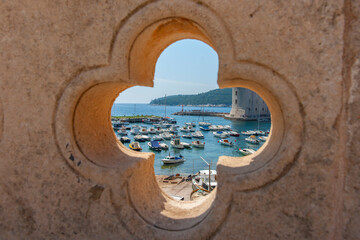 View through characteristic rosette shaped opening in Old Town wall to bay and boats.