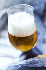 Glass of beer on bright wooden background. Copy space.