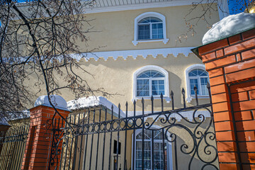 A mansion behind an iron fence on a winter day