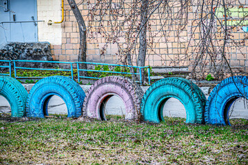 A fragment of a sidewalk fence made of old tires on a spring day