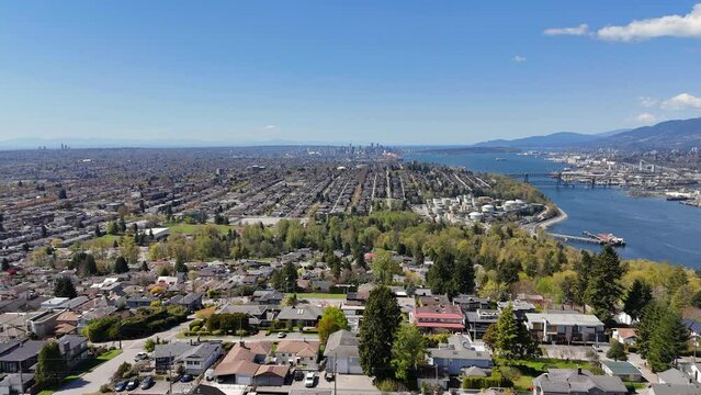 Panoramic aerial drone view (boom up) of the skyline of Vancouver and Burnaby next to the Burrard Inlet during a spring season in British Columbia, Canada