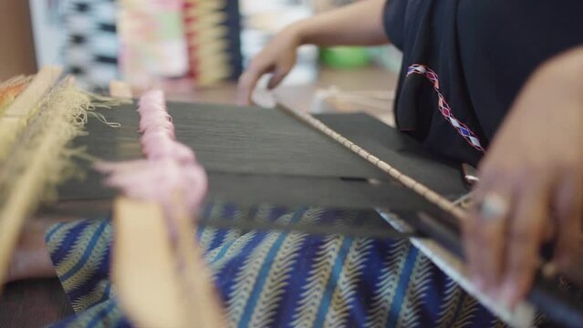 An Indonesian woman weaving traditional lombok fabric, Tenun or Weaving is a technique in the manufacture of fabrics which is made with combining thread lengthwise and transversel.
