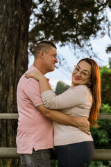 Beautiful adult couple in love talking and looking at their natural surroundings, daydreaming. Happy romantic husband and wife outdoors. Mother's day, family and father's day. Trees.