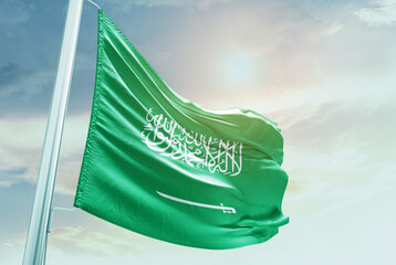 Saudi Arabia flag in waving in beautiful sky with sunlight.