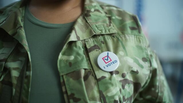 Close up of anonymous military man putting on badge with American flag logo and inscription I Voted. US Army representative at polling station during elections. National Election Day in United States.