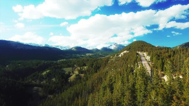 Aerial Scenic View Of Tranquil Snowcapped Mountains, Drone Flying Forward Over Green Forest Trees On Sunny Day - Flathead National Forest, Montana