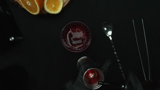 Top down view of bartender hand making and prepare Scarlet spritzer with black background. Close up of smart bartender hands presenting and making red cocktail with lemon slice decorated. Comestible.