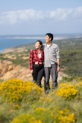 A couple standing on a hillside with a beautiful view of the ocean