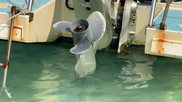 Close up stainless steel motor boat propeller on turquoise sea water background.	