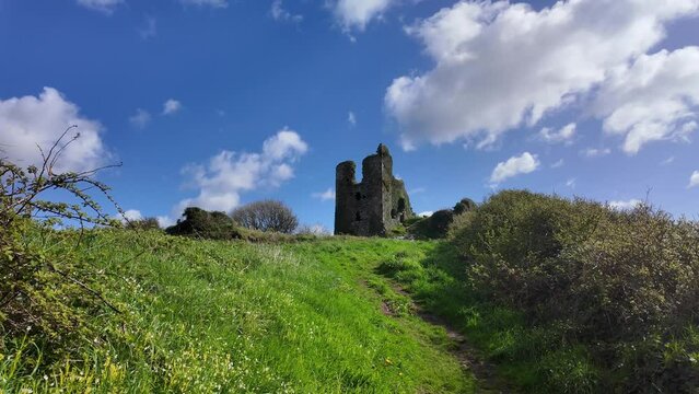 Rural scene path to historic Dunhill medieval castle on a beautiful spring day with blue sky skies and bright clouds moving by landscape scene in Waterford Ireland