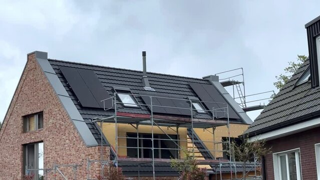 New Home during building phase with modern solar panels on construction site. Cloudy day in german neighborhood. Medium shot.