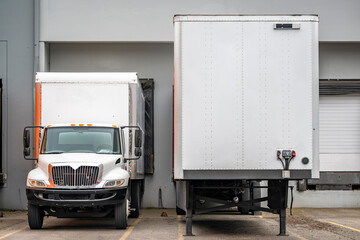 Middle duty day cab rig semi-truck with box trailer and dry van semi trailer standing on the...